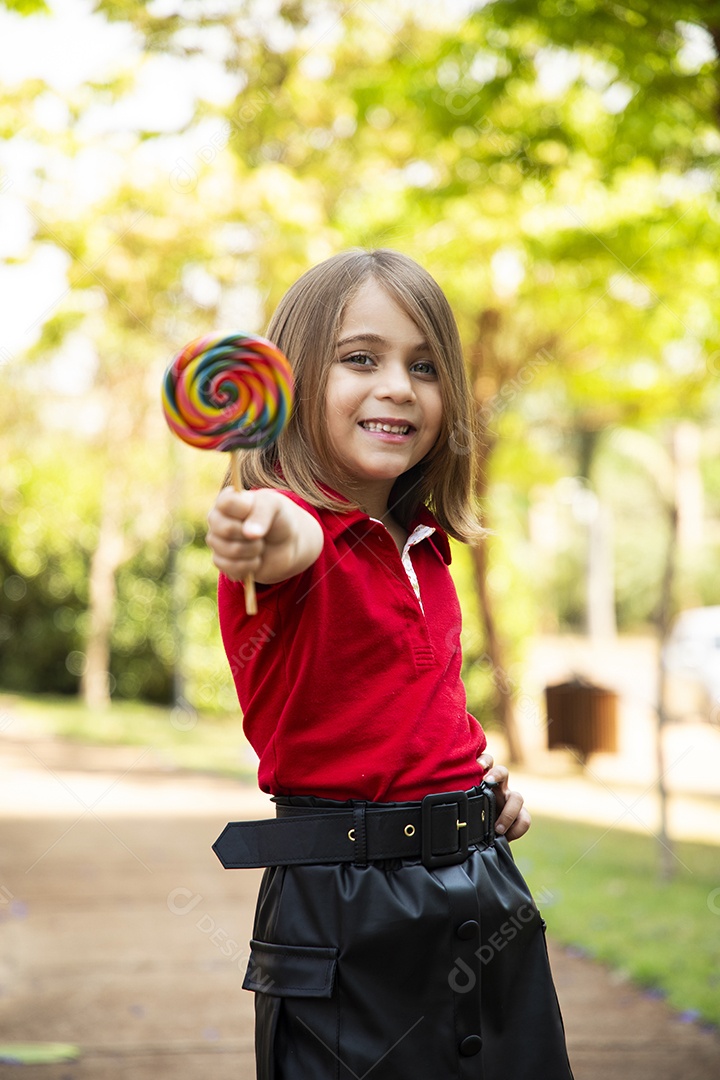 Menina fofa sorrindo com pirulito na mão