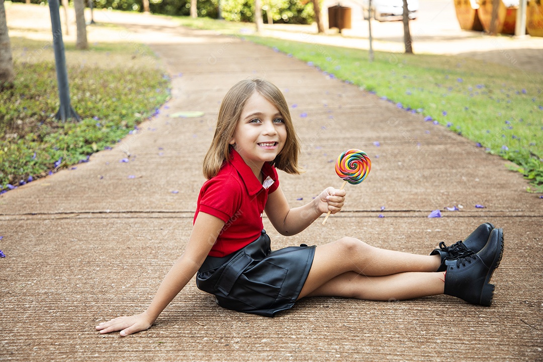Menina fofa sentada chupando pirulito