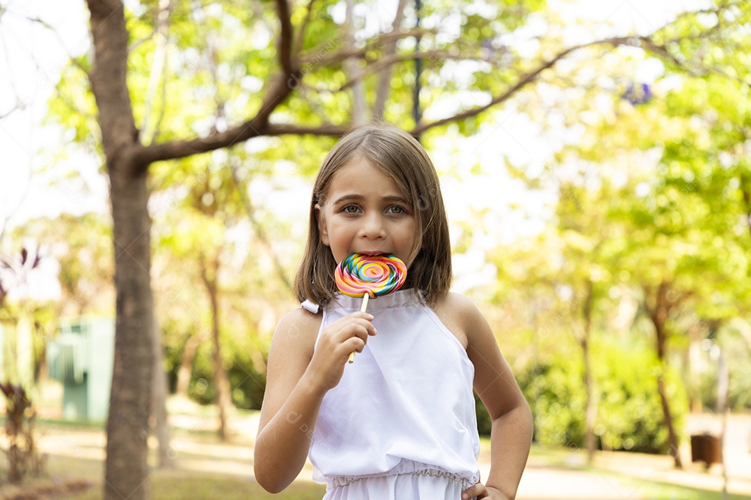 Menina loira linda sorrindo para fotos chupando pirulito