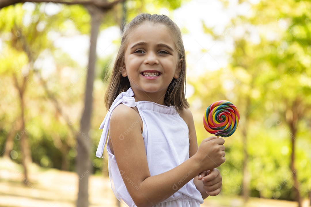 Menina fofa sorrindo com seu pirulito nas mãos