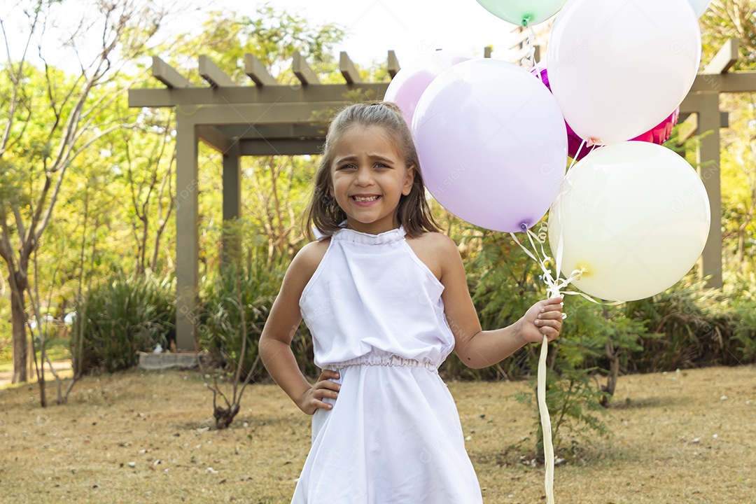 Menina fofa segurando muitos balões para foto