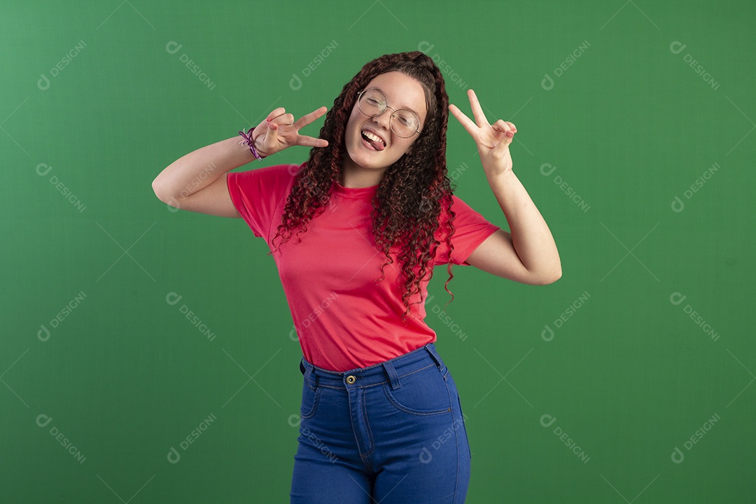 Menina cacheada divertida com dedos para cima e careta