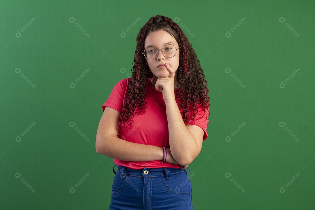 Menina cacheada com mão no queixo gesto de pensativa