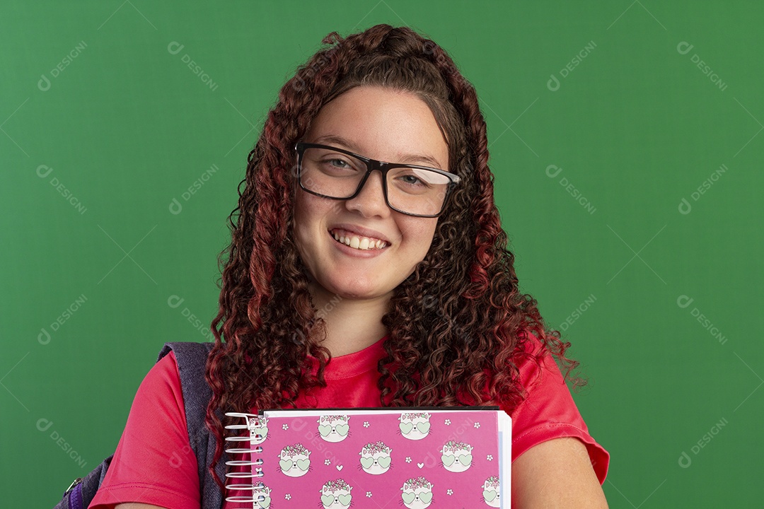 Menina sorrindo com cadernos nas mão e mochila nas costa