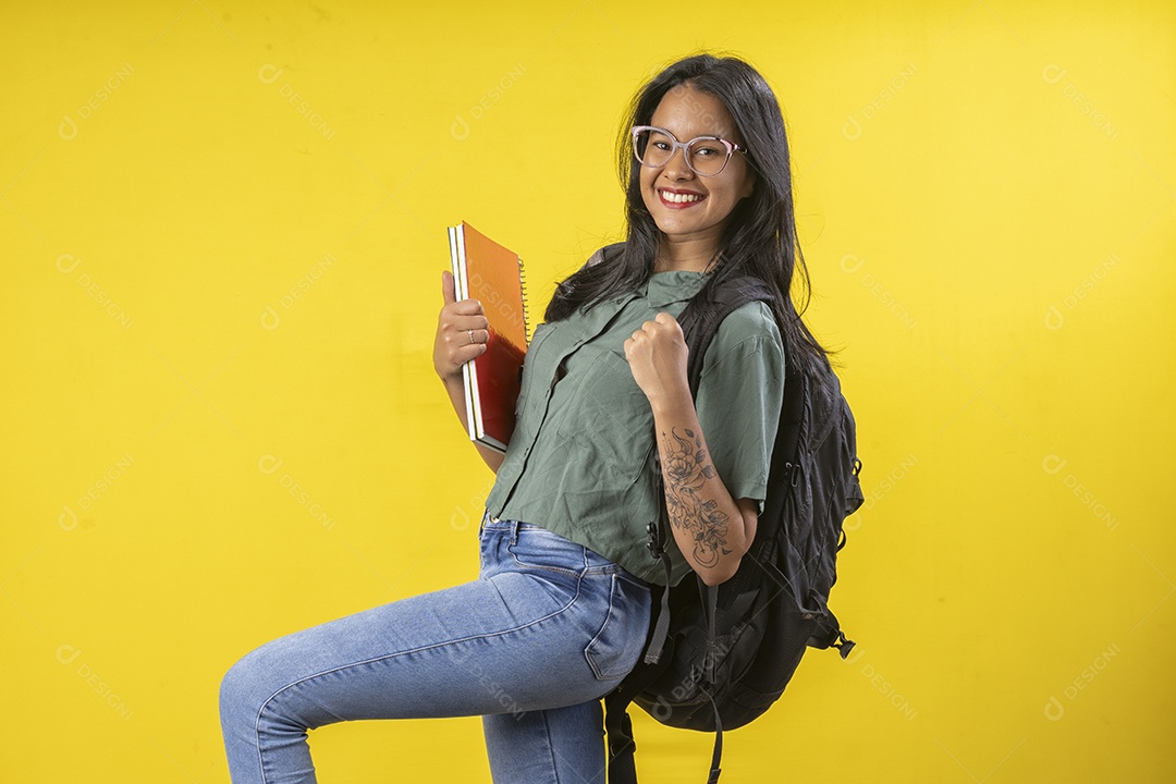 Jovem feliz segurando livros e com mochila nas costa