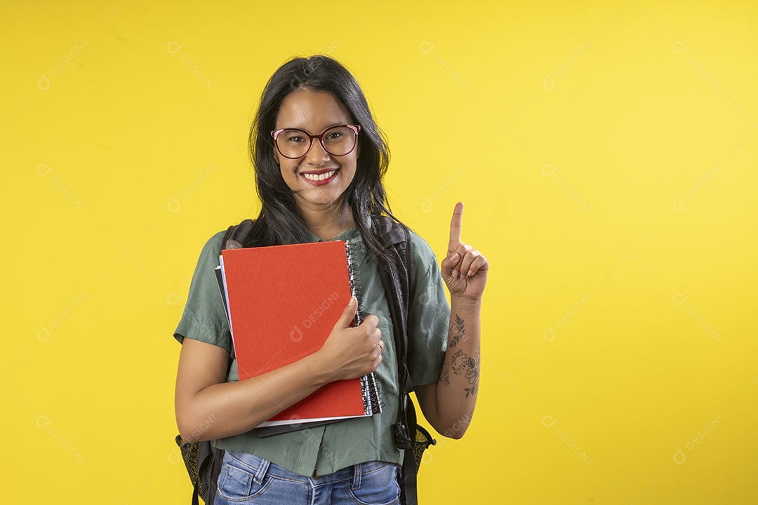 Jovem com muitos livros na mão apontando para cima
