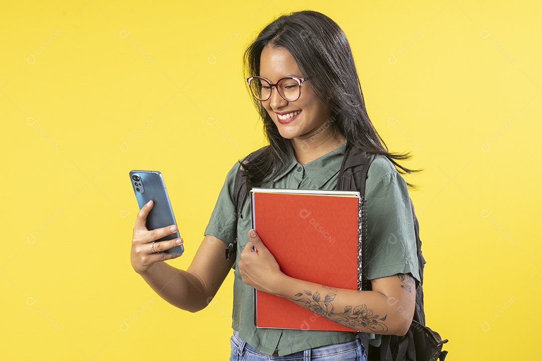 Garota com livros e mochila nas costas usando celular