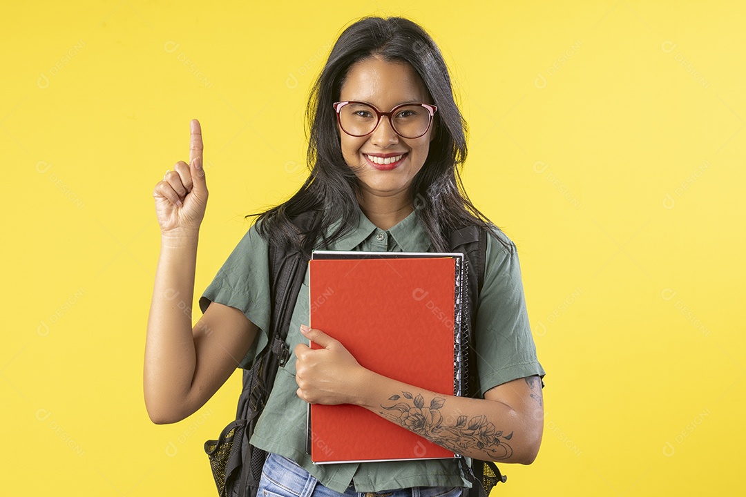 Jovem apontando dedo para cima e segurando livros nas mãos