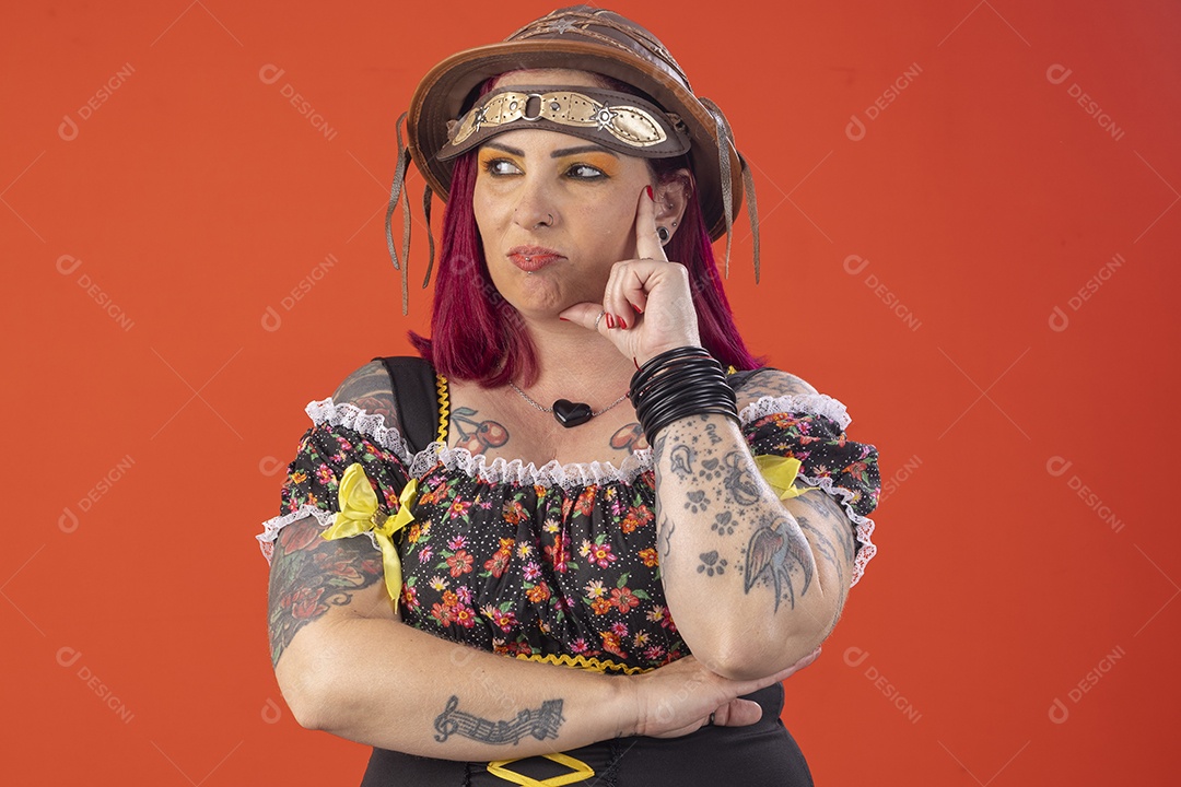 Uma mulher com trajes junino e mão no rosto pensativa