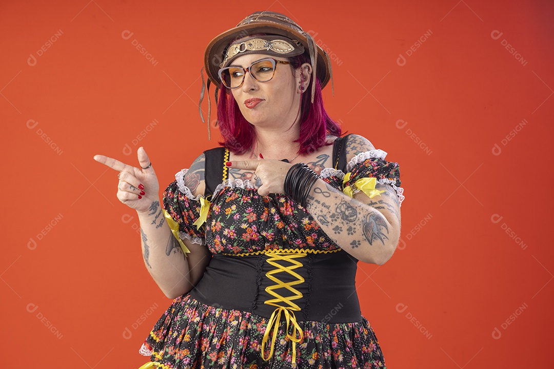 Jovem garota com trajes juninos sorrindo apontando para lado