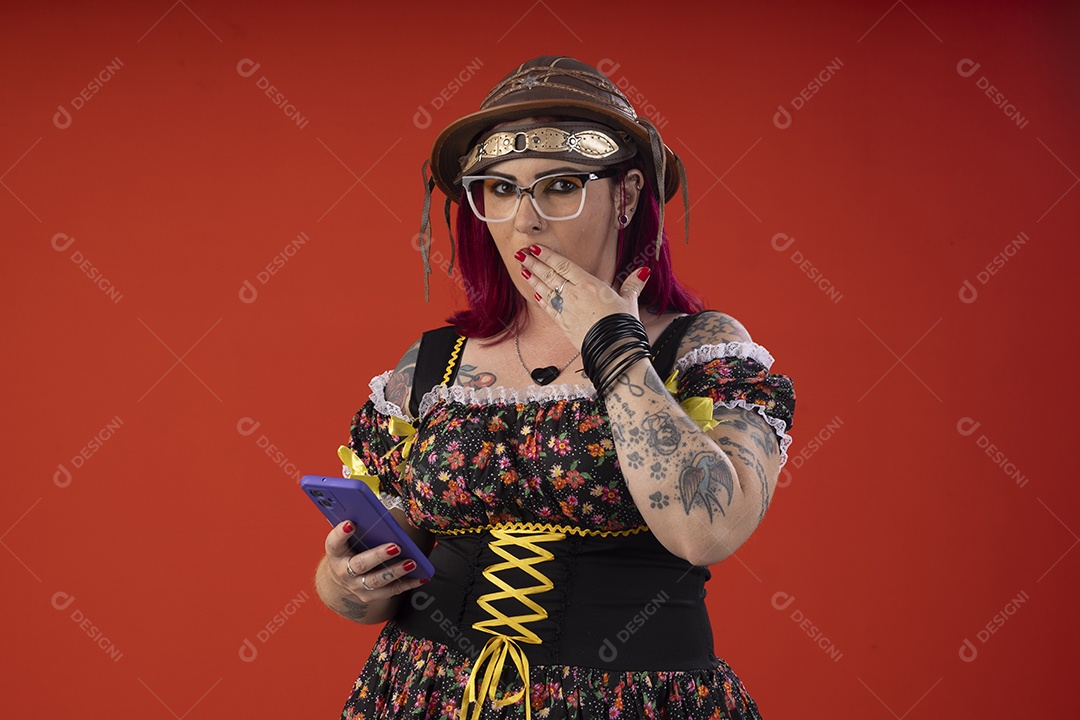 Mulher com trajes juninos com gesto de mostrar o celular