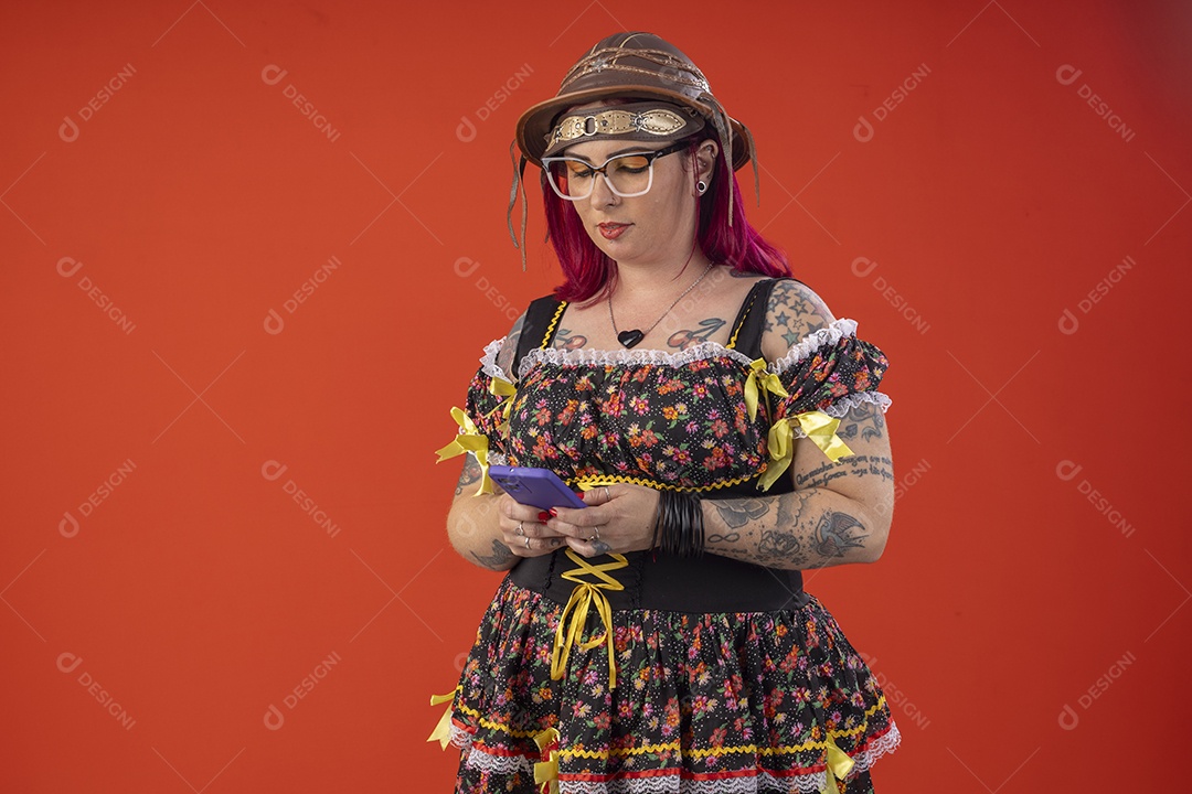 Uma mulher vestida a caráter para festa junina com celular na mãos
