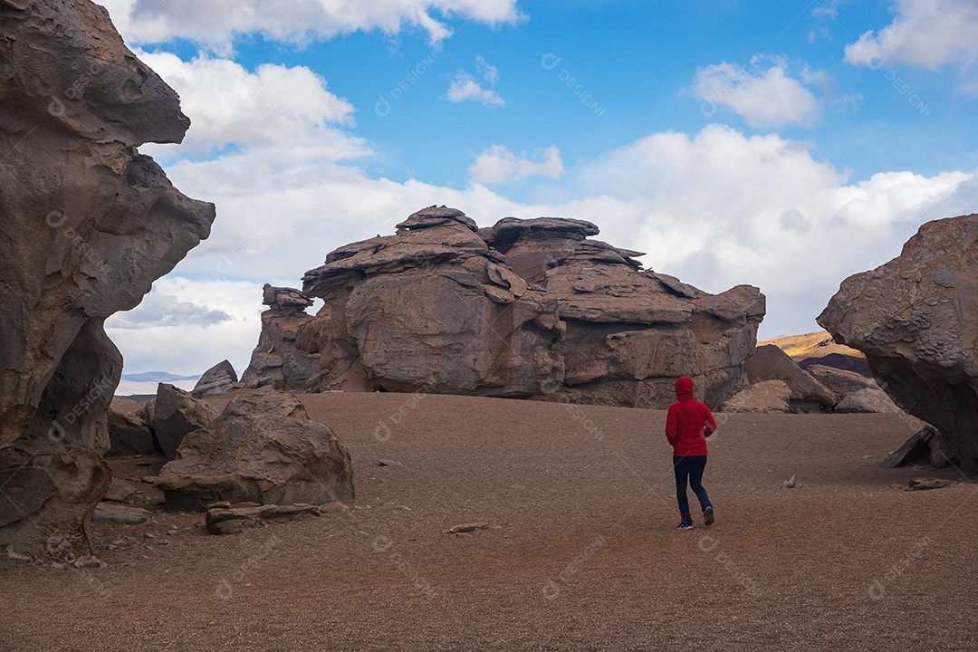 Turista caminhando entre rochosas formadas pela erosão no deserto da Bolívia
