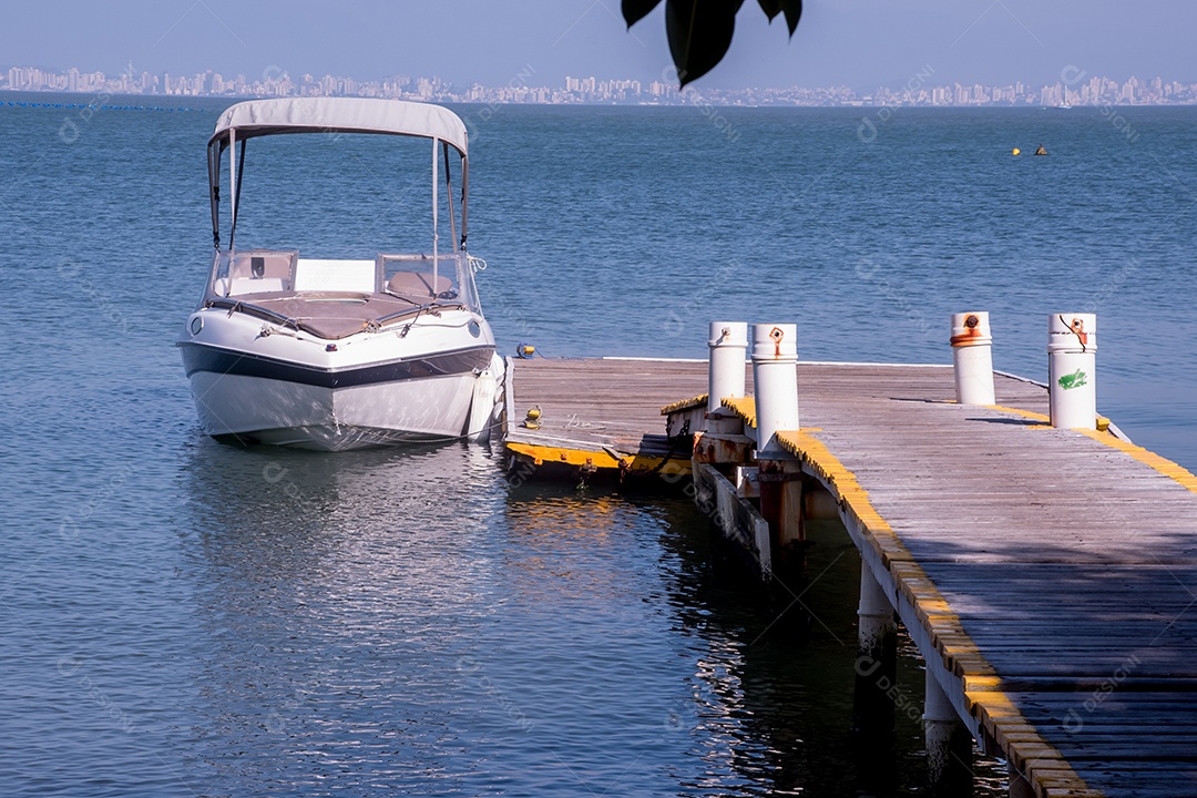 Barco ancorado no mar próximo à plataforma de madeira