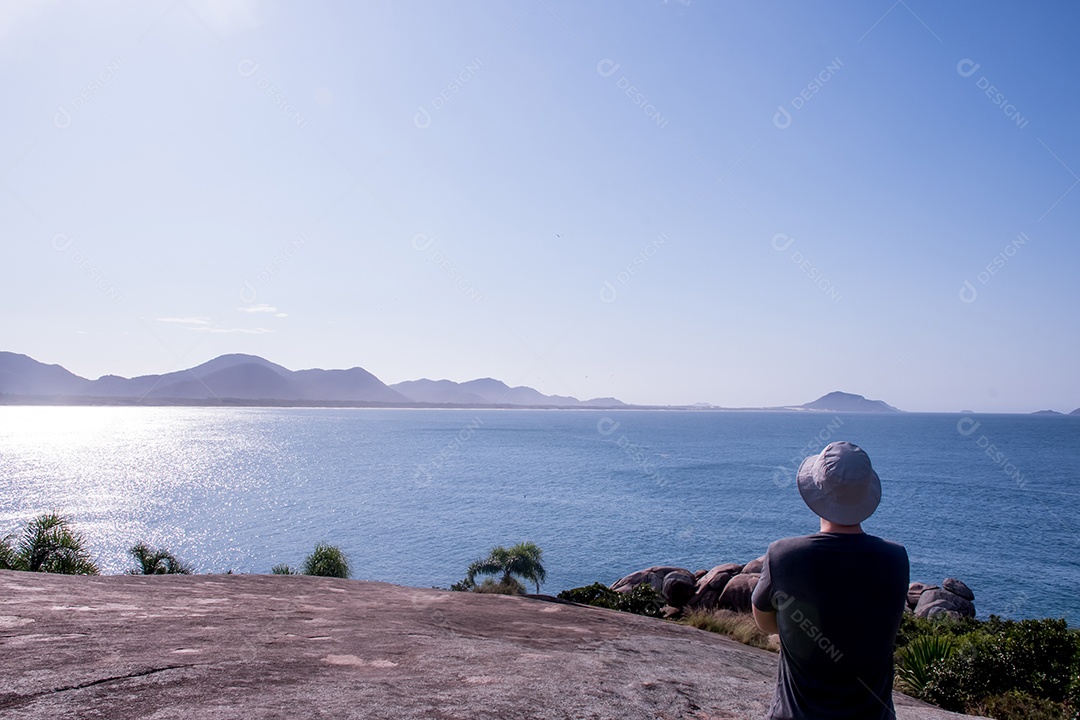 Homem de chapéu olhando para o mar