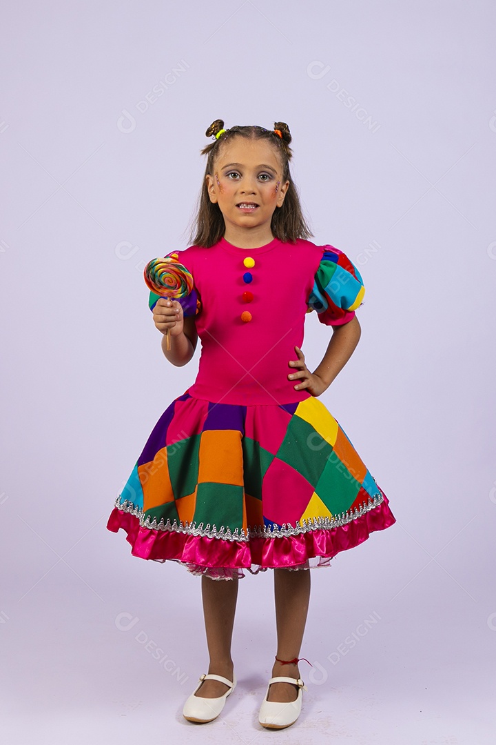 Menina fofa fantasiada com uma roupa colorida com um pirulito na mão