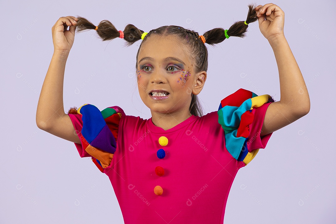 Menina fofa feliz segurando tranças vestida de roupa colorida