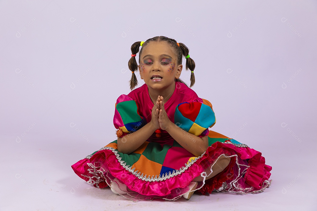 Menina fofa com roupa colorida sentada no chão com mãos dadas