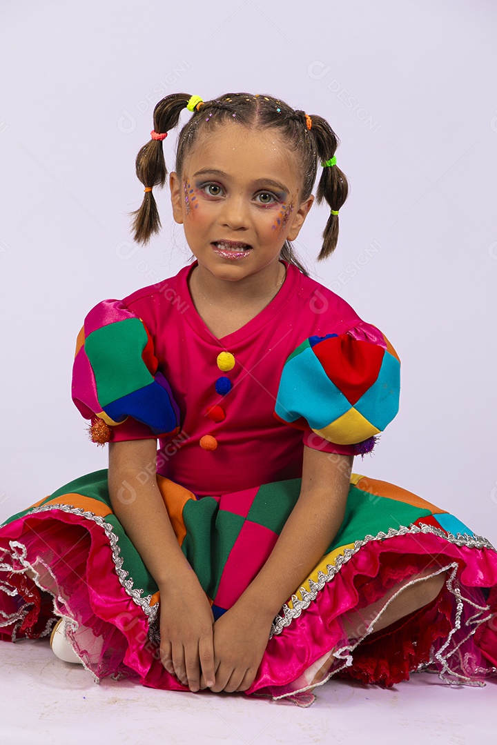 Menina fofa com roupa colorida sentada no chão sorrindo