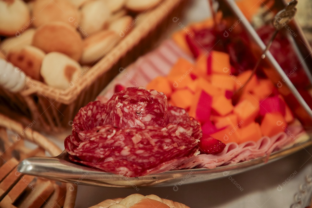 Travessa de frios e ao fundo uma cesta com biscoito