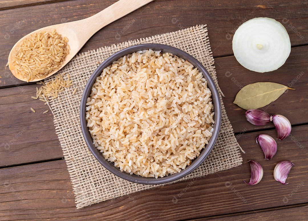 Arroz integral cozido em uma tigela sobre a mesa de madeira com cebola