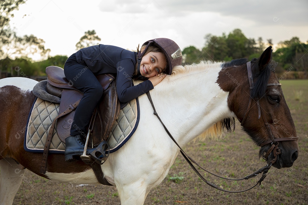 Cute little girl mounted on a horse practicing riding