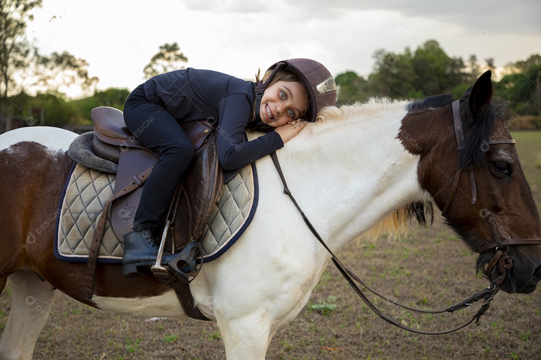 Garotinha fofa montada em um cavalo praticando montaria