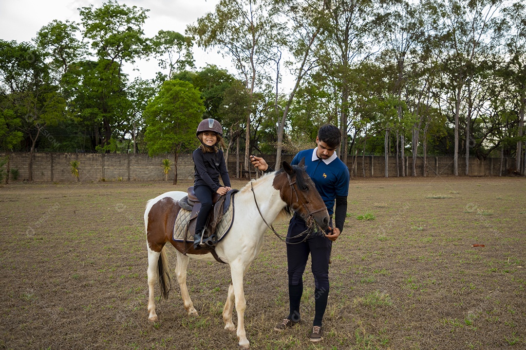 Garotinha feliz praticando hipismo