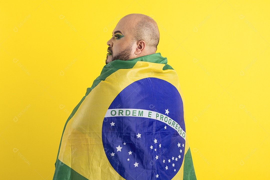 Jovem gay maquiado e coberto com bandeira do brasil