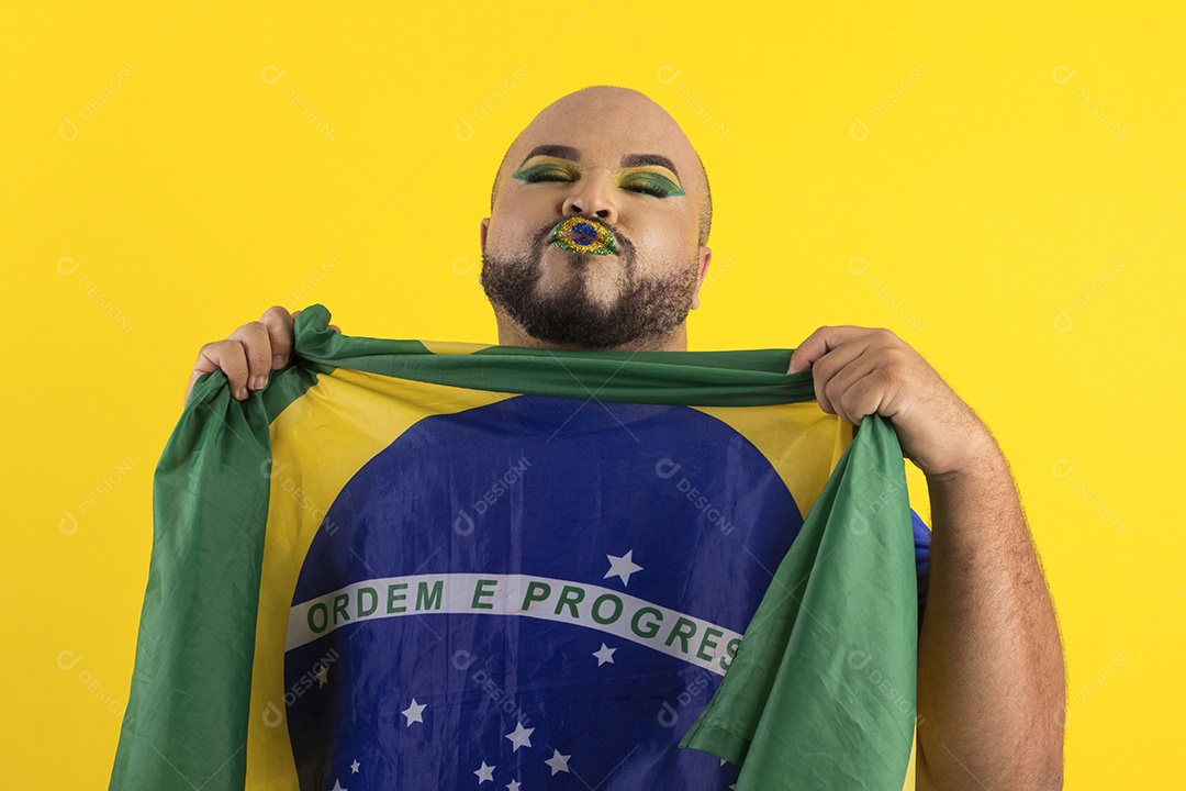 Jovem maquiado segurando bandeira do brasil fazendo pose de bico