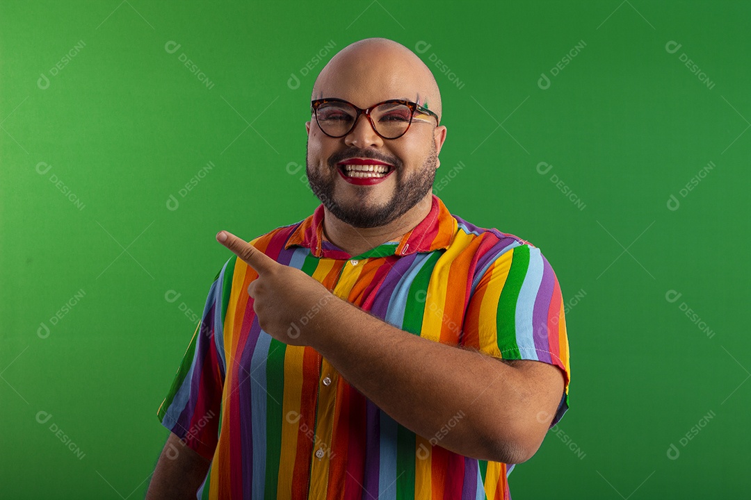 Homem gay feliz com roupa colorida sorrindo apontando para o lado