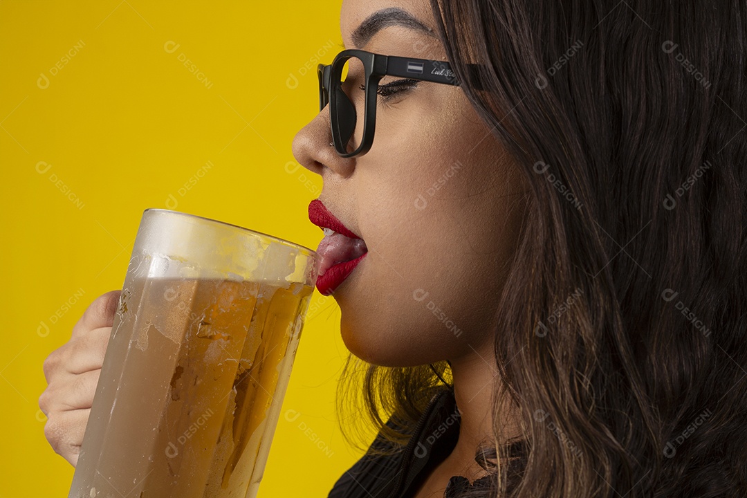 Uma jovem bonita e sexy com a língua na beira da caneca de chope