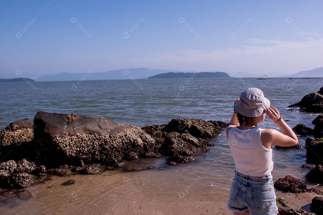 Mulher com chapéu olhando para o mar