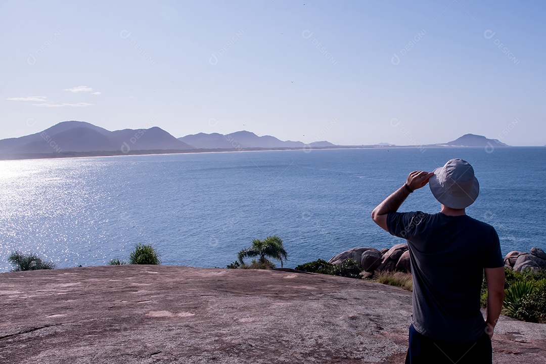 Homem com chapéu olhando o mar piscinas naturais