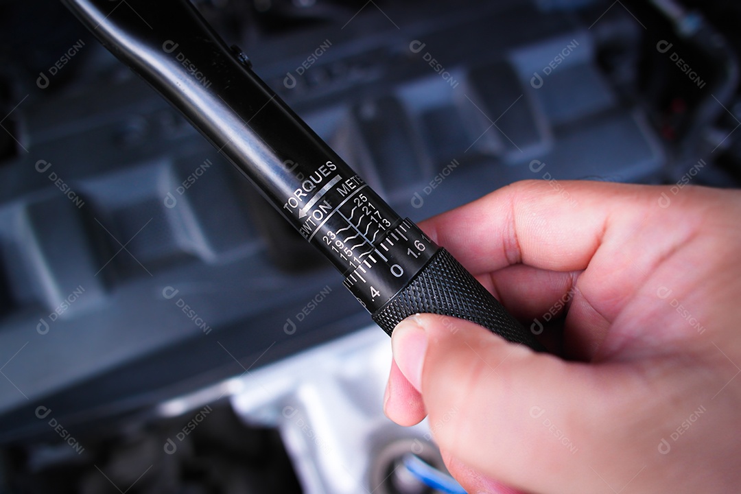 Mecânica de automóveis segurando a chave de torque sobre o motor do carro