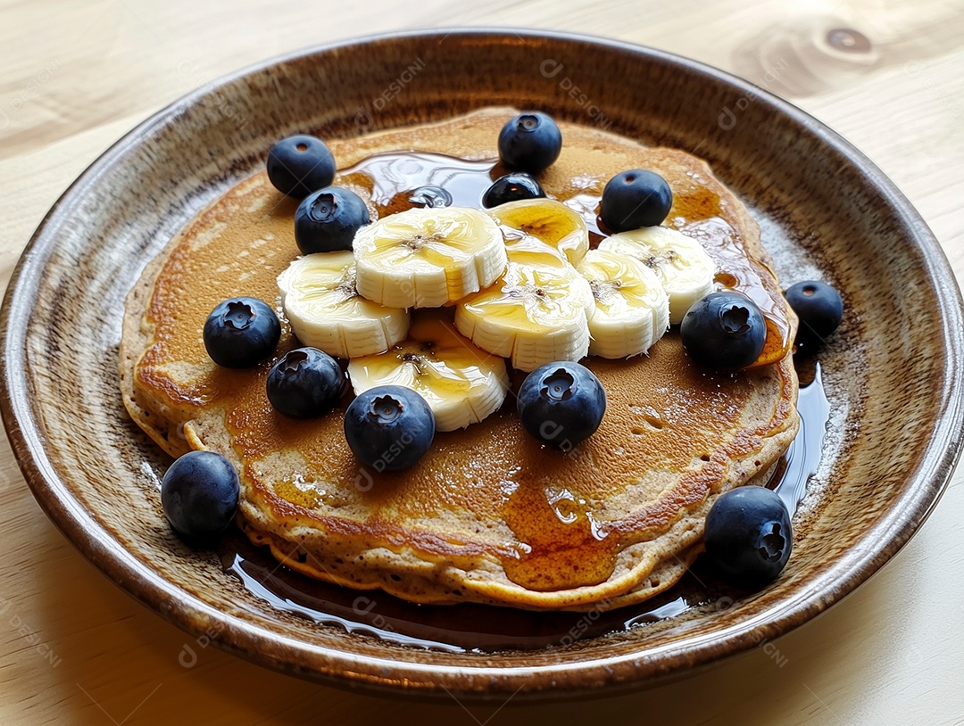 Panquecas com mel banana e mirtilo em prato sobre mesa de madeira