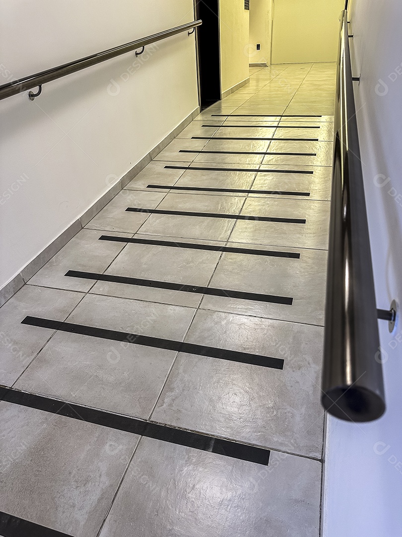 Piso do corredor com faixa antiderrapante e corrimão para segurança