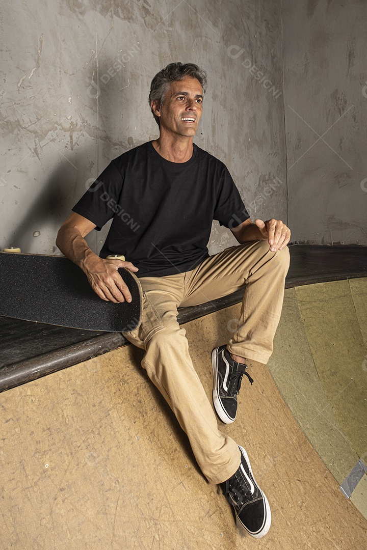 Homem de meia idade feliz com seu skate do lado