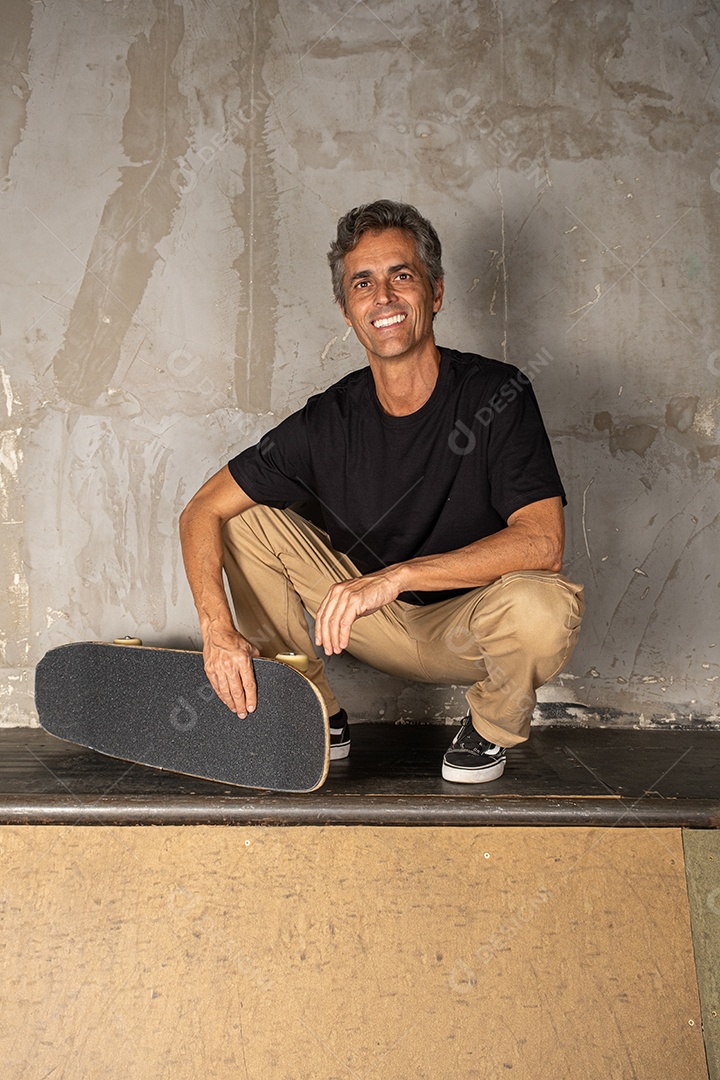 Homem de meia idade descolado com skate na mão