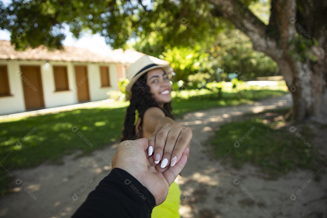 Jovem felliz segurando a mão de alguem em um lindo lugar