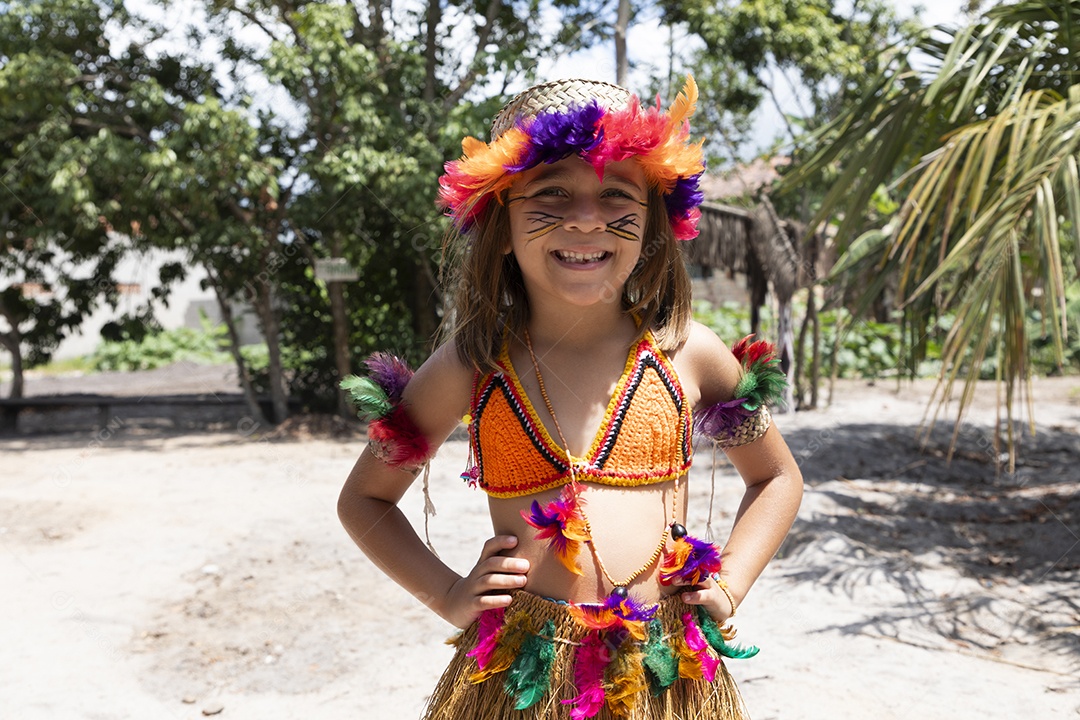 Uma garotinha feliz na aldeia com roupas indígenas