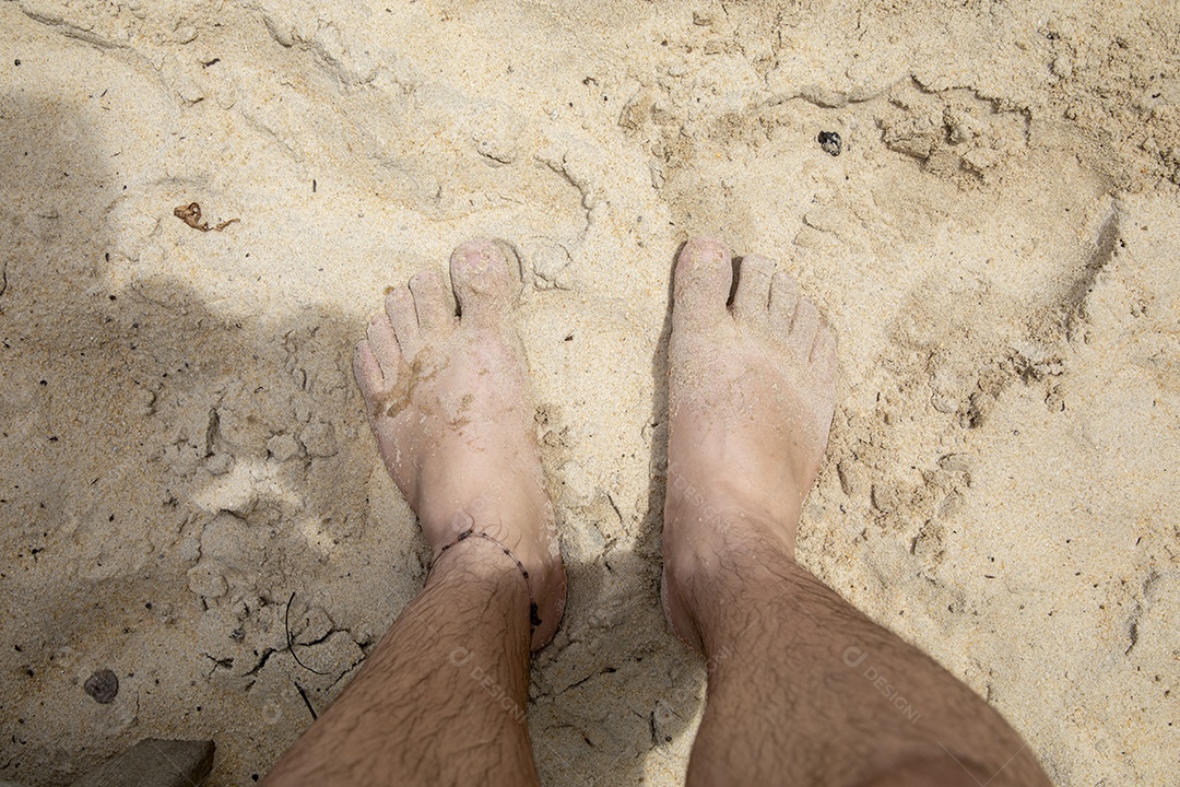 Homem com pés na areia de uma praia