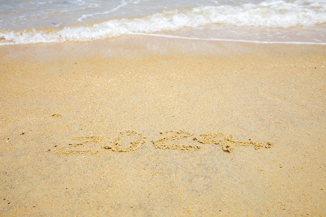 Areia da praia com numeros 2024 e ondas do mar
