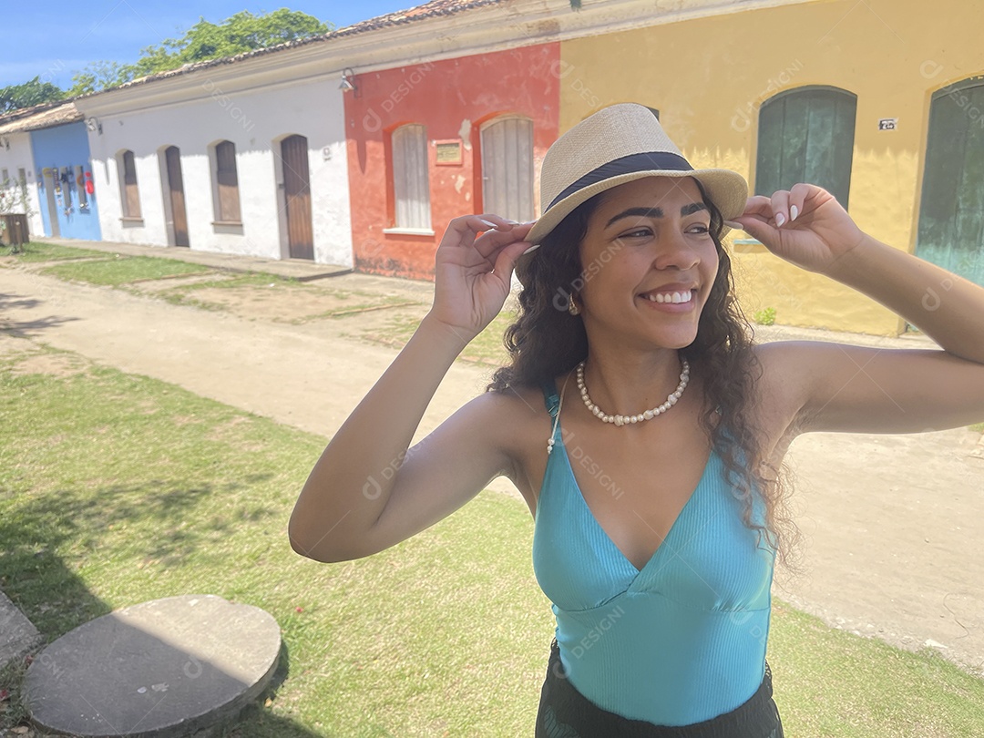 Mulher jovem feliz com mãos no chapéu