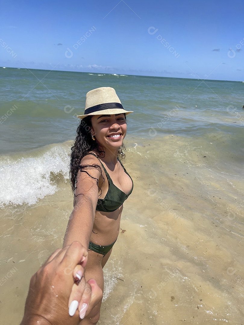 Jovem linda na praia usando chapéu