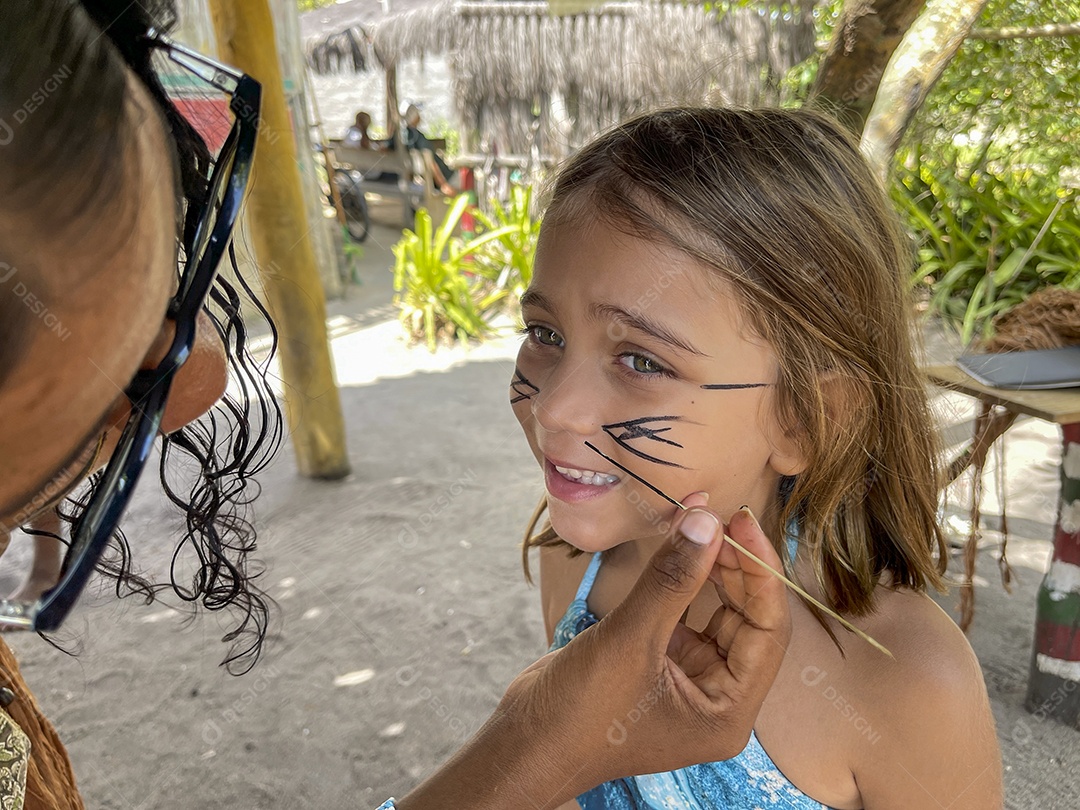 Mulher india pintando o rosto da menina linda