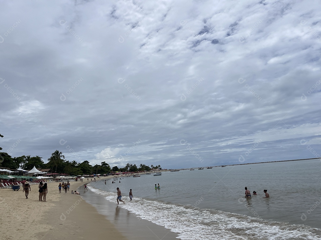 Praia com ondas do mar e banhistas aproveitando