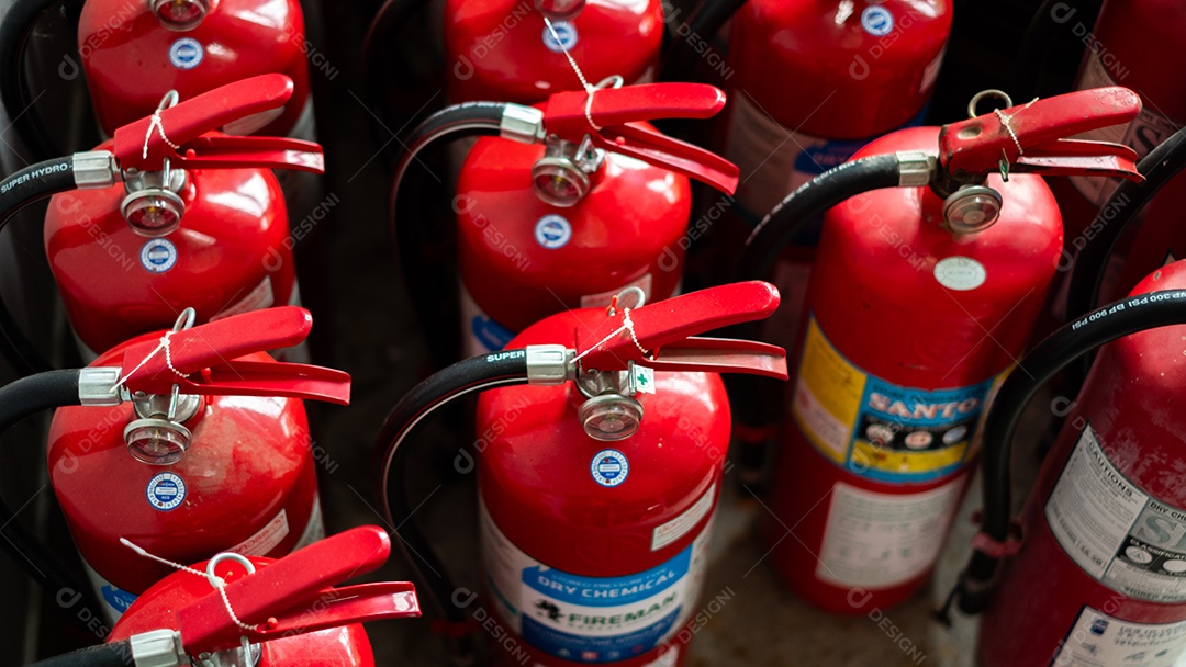 Muitos extintores de incêndio vermelhos são colocados no chão preparados para incidentes de incêndio