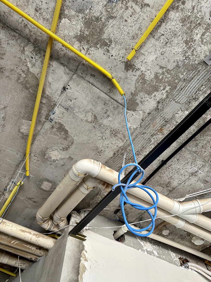 Instalação de teto com tubos e conduítes em canteiro de obras