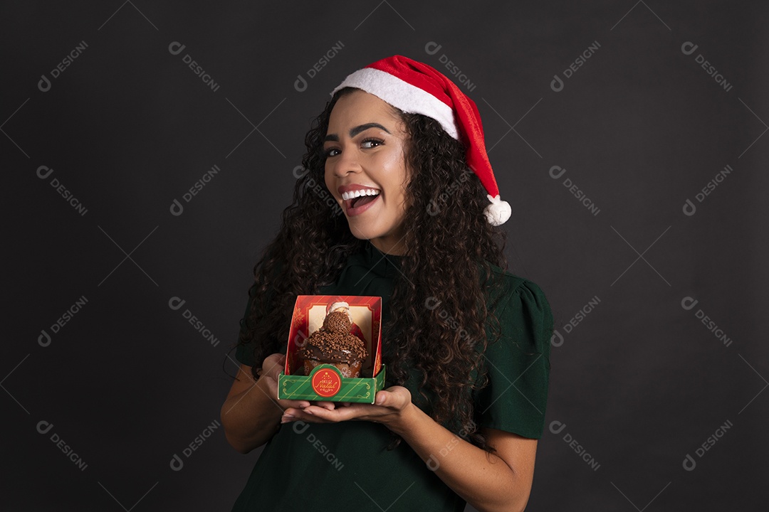 Mulher usando gorro vermelho e segurando caixa com panetone